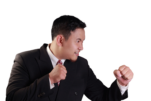 Business concept image of an Asian businessman ready to fight with his punch isolated on white