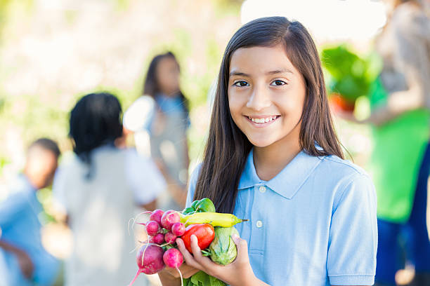istock Student holding vegetables she picked from garden during field trip 498196790
