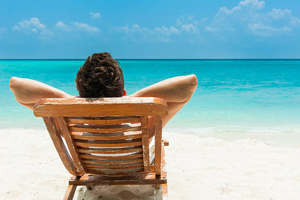 joven descansando en la playa - tomando el sol fotografías e imágenes de stock