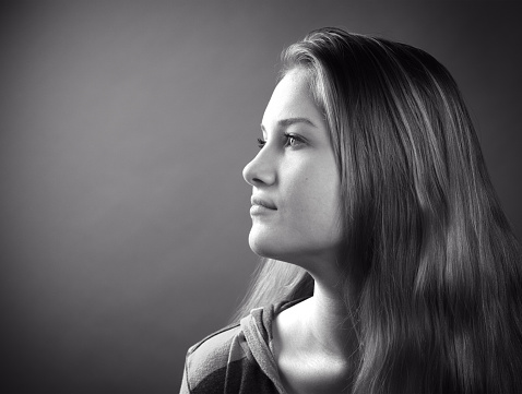 Studio black and white portrait of a young woman or late teenager.  Fine art portrait in profile view with great copy space image left.  Woman has a classic, timeless look and very proud.