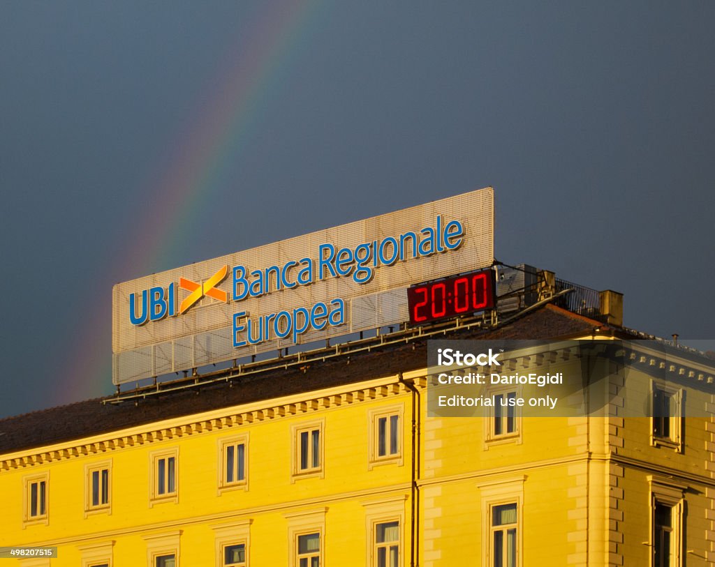 Signboard of UBI Bank on yellow palace, rainbow on background Turin, Italy - April 29, 2014: Symbol of UBI bank located on the roof of a building in the center of the city of Turin in Italy. Rainbow Stock Photo