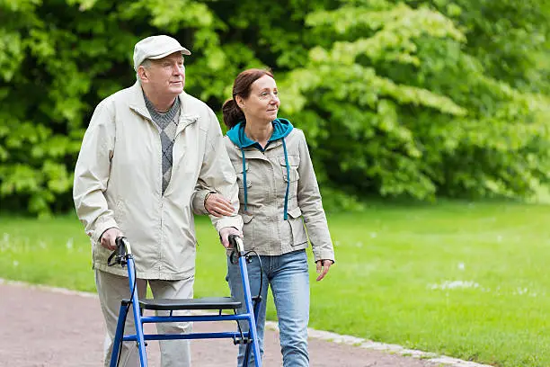Assistance living – senior man with walker and caregiver