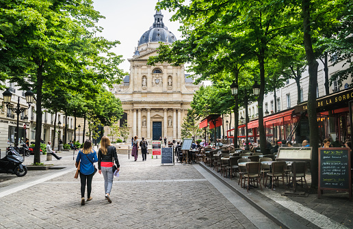 Paris, France - May 25, 2014: Two young women walk past the many outdoor cafes and restaurants in Sorbonne Square as they head for the  Pantheon, Sorbonne University