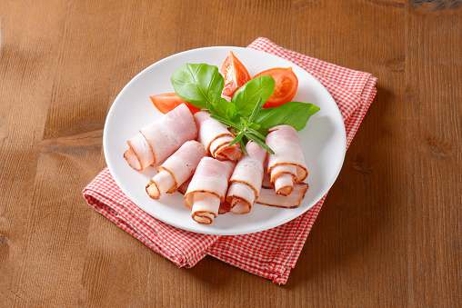 bacon rolls with vegetable garnish on white plate and chequered placemat