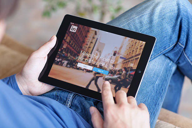 uomo che tiene un ipad con app linkedin sullo schermo - touching mail connection business foto e immagini stock