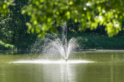 Fountain in the park on a blurred background foliage