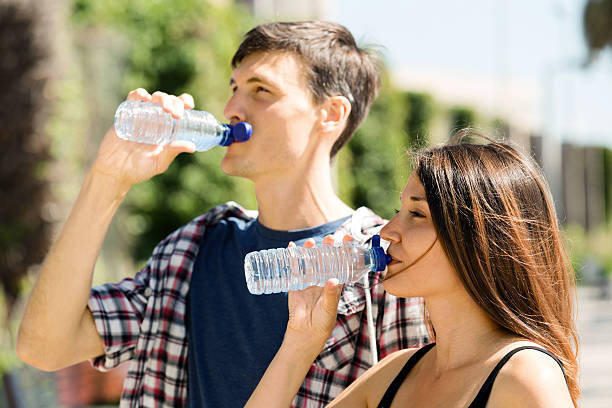 istock couple drinking water from plastic bottles outdoor 498236973