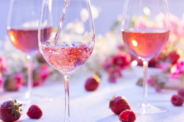 Summer Rosé Glass of rosé wine being poured at a picnic setting on a summer's day. rose wine photos stock pictures, royalty-free photos & images