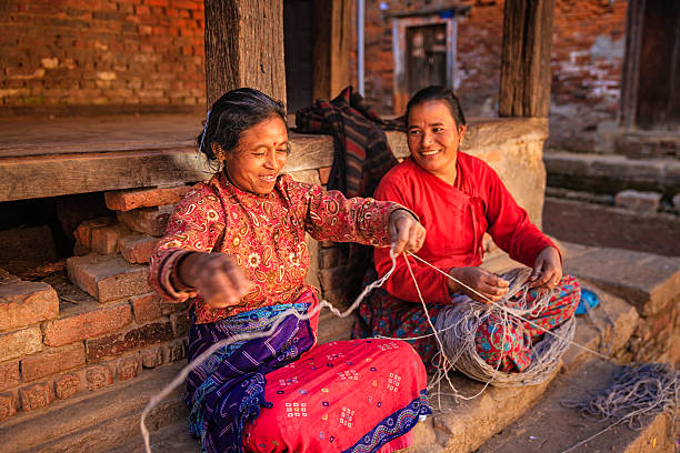 zwei nepali frauen spinnen wolle in bhaktapur, nepal - katmandu stock-fotos und bilder