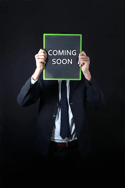 Photo of Businessman with coming soon written on slate