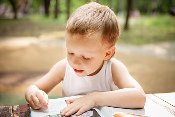 istock Little boy reading a book in the park 498242231