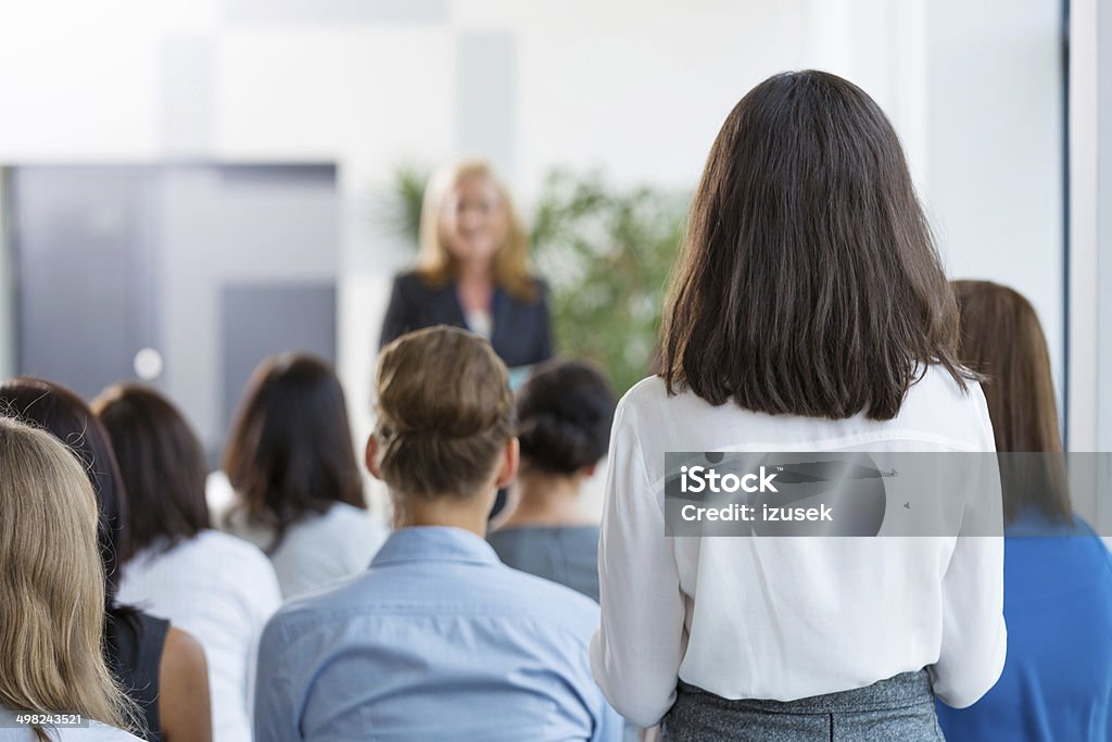 Seminar for women Group of businesswomen attending a seminar. Focus on woman aking question. Rear View Stock Photo