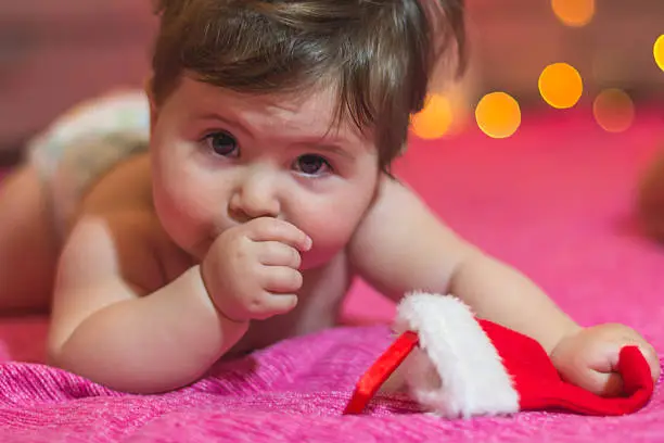 cute baby girl lying and waiting for gift on new year's eve  , lying naked with new year's decorations, ornaments ,sock ,