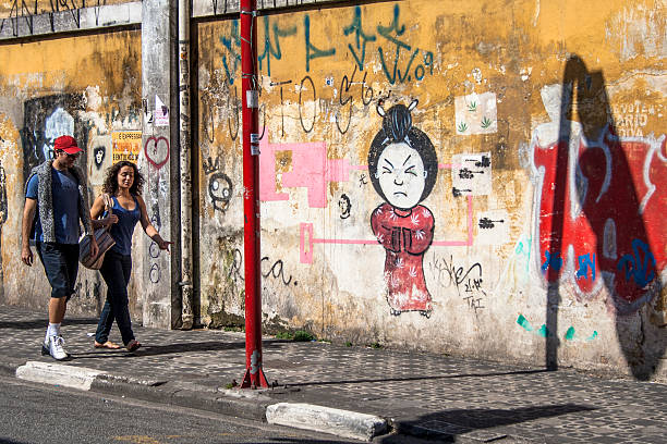 Young woman artist expressing creativity by painting a vibrant graffiti mural featuring the word love on an urban wall