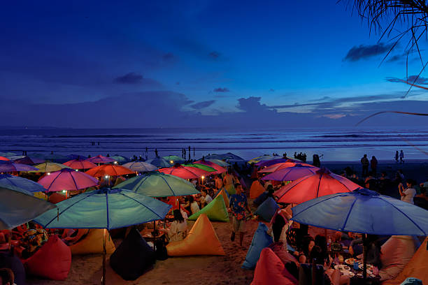 Seminyak, Indonesia - May 03, 2015: People chill out in Seminyak's beach bar after sunset, under colourful parasols.