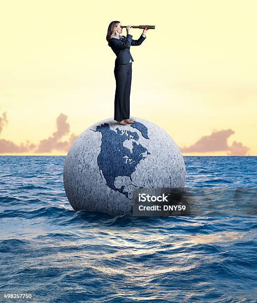 Businesswoman Looking Through Spyglass Standing On A Globe Stock Photo - Download Image Now