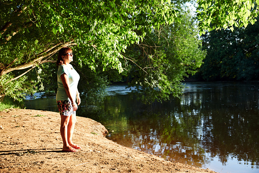 Mature smiling hispanic standing on riverbank in the Dordogne in France with lots of copy space