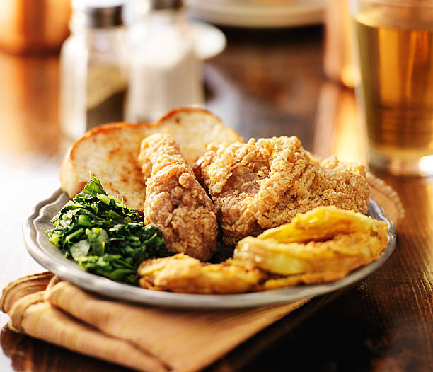 southern soul food with fried chicken and collard greens southern soul food with fried chicken and collard greens shot with selective focus on wooden table southern usa stock pictures, royalty-free photos & images