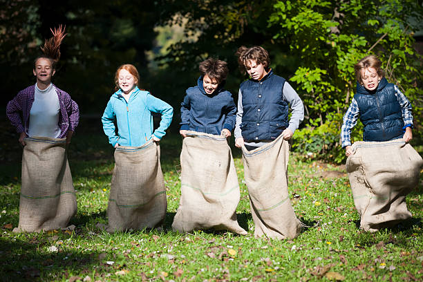 grupo de crianças felizes se em uma corrida de saco - child playing sack race sports race - fotografias e filmes do acervo