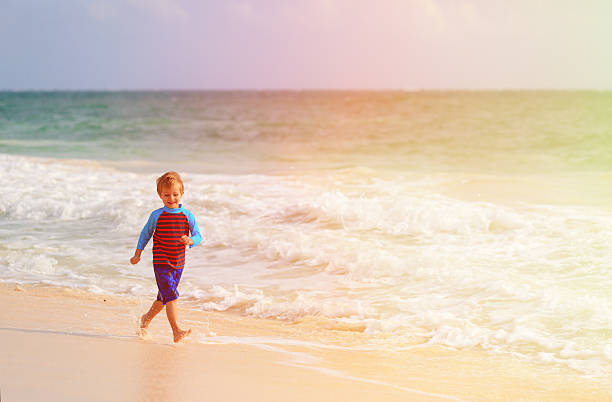 istock happy little boy running on sand beach 498273946