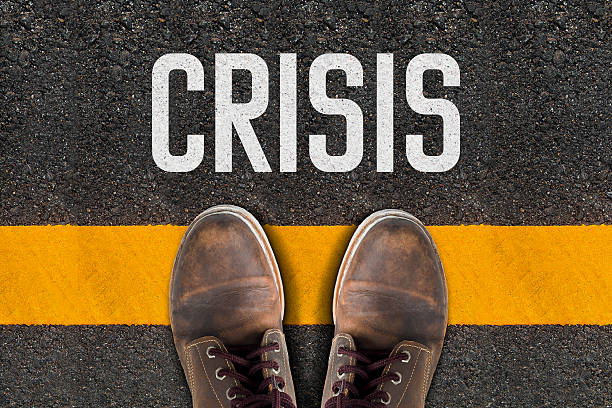 istock Shoes over Yellow Line   and Crisis Printed On The Road 498281130