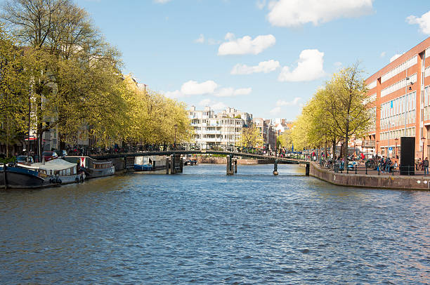 амстердам городской пейзаж в начале весны, waterlooplein справа. - europe sunlight river sun стоковые фото и изображения