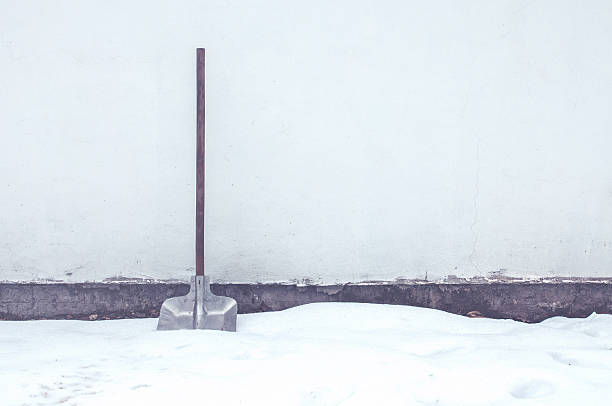 Retro toned snow shovel in a deep snow leaning on to house wall, winter season image with copy space