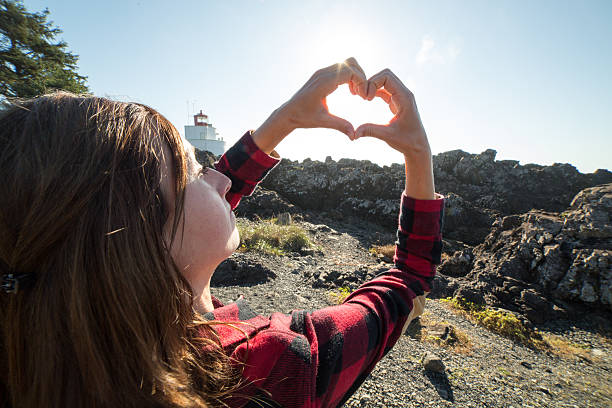 istock Young woman on the cliffs makes heart shape finger frame 498298012