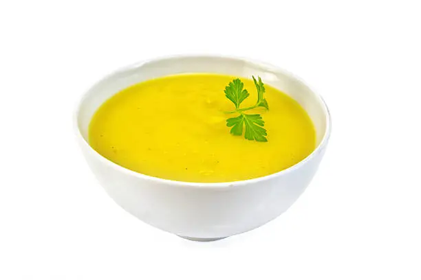 Soup-puree pumpkin with parsley in a white bowl isolated on white background