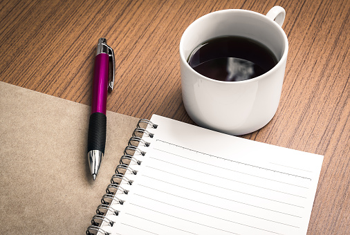 Pen on empty notebook and coffee over wood table  ( workplace concept )