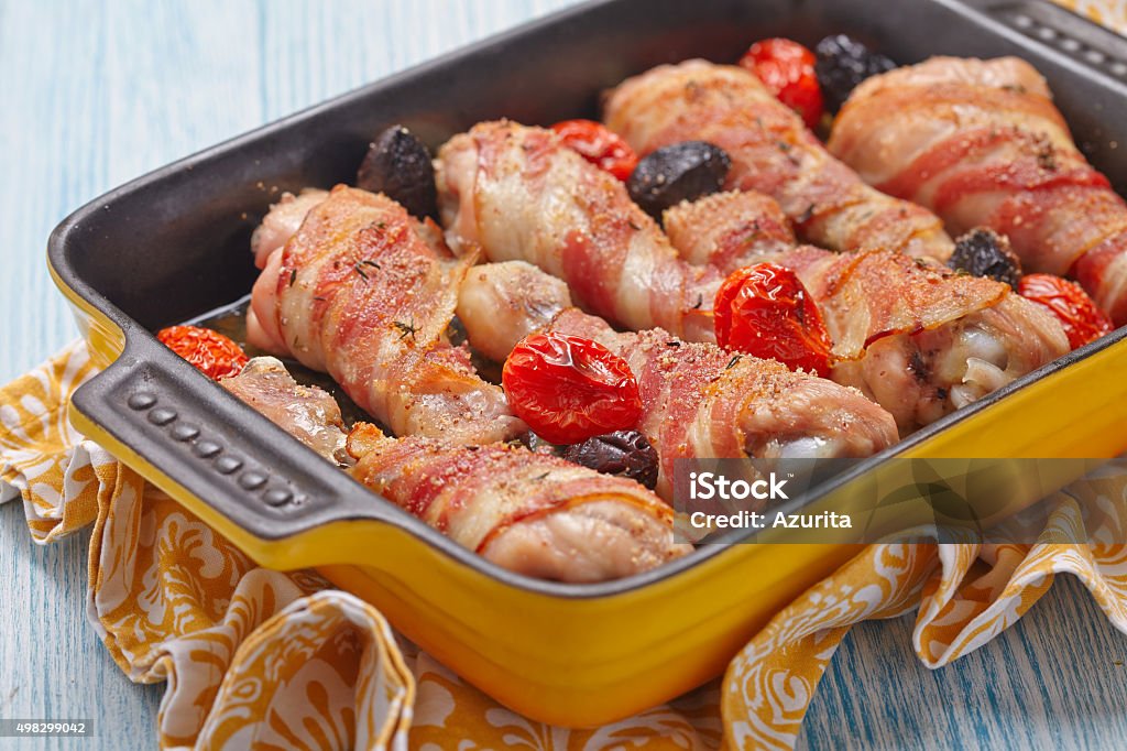 Bacon wrapped chicken legs Bacon wrapped chicken legs with tomato and olives 2015 Stock Photo