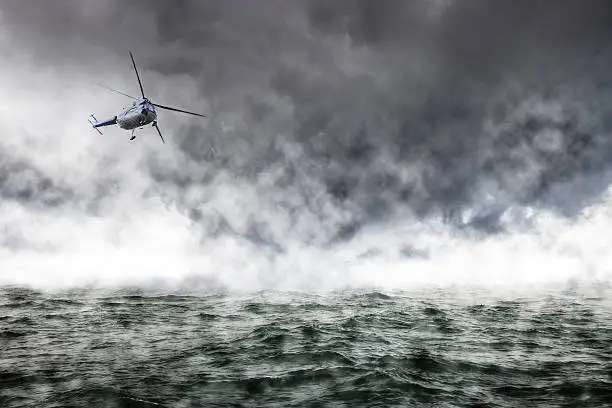 A helicopter rescue mission in difficult stormy weather at sea.