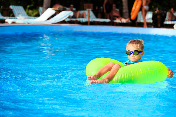 маленький мальчик в жизнь кольцо весело на бассейн - water park inflatable ring water swimming pool стоковые фото и изображения