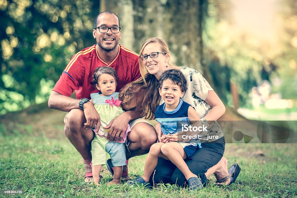 Happy interracial family is enjoying a day in the park Happy interracial family is enjoying a day in the park. Little baby girl and boy. Successful adoption. Diverse family in nature with sun in the back. Family Stock Photo