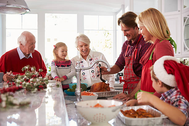 istock Extended Family Group Basting Christmas Turkey In Kitchen 498304890
