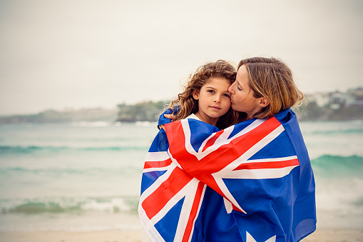 Mother kissing daugther and they are covered by Australian flag