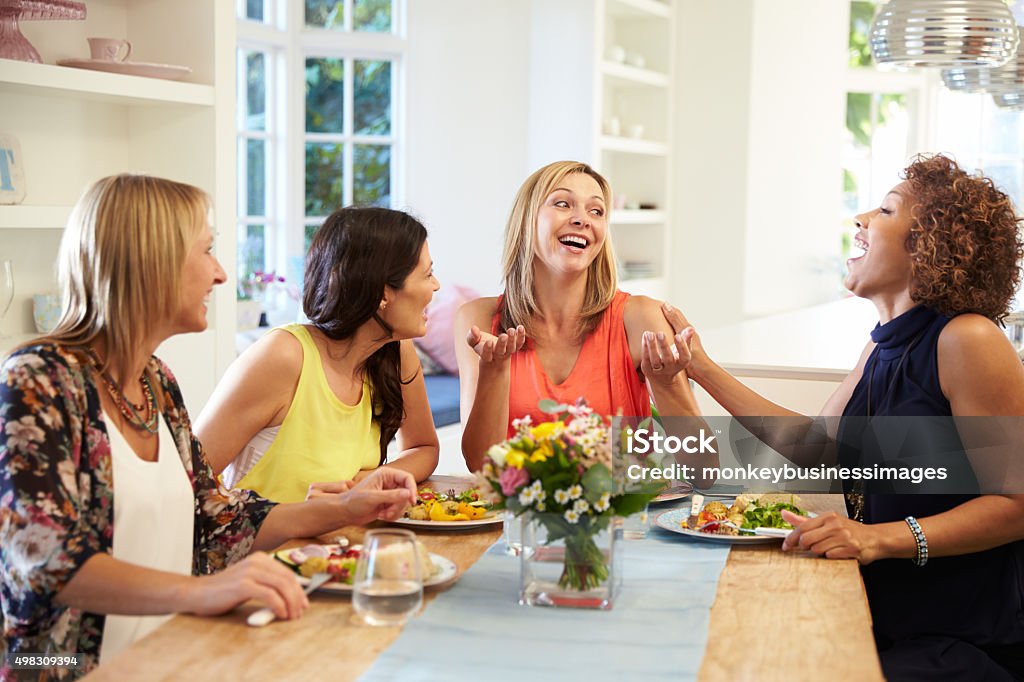 Mature Female Friends Sitting Around Table At Dinner Party Mature Women Stock Photo