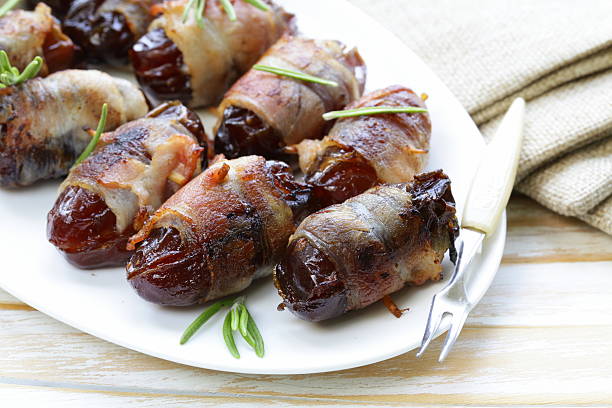 appetizer delicacy dates wrapped in bacon and fried appetizer delicacy dates wrapped in bacon and fried bacon wrapped stock pictures, royalty-free photos & images