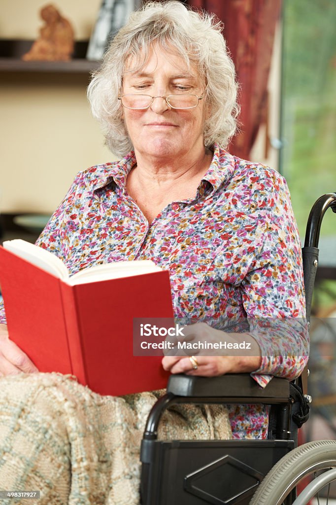 Senior donna In sedia a rotelle lettura libro - Foto stock royalty-free di 70-79 anni