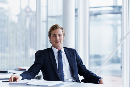 Portrait of handsome businessman sitting at desk in office