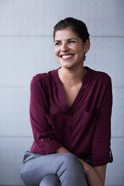 Happy businesswoman in office Happy businesswoman looking away while sitting in office three quarter length stock pictures, royalty-free photos & images