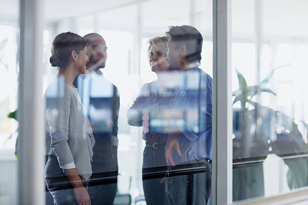 Businesspeople conversing in office View of businesspeople conversing through glass wall in office differential focus stock pictures, royalty-free photos & images