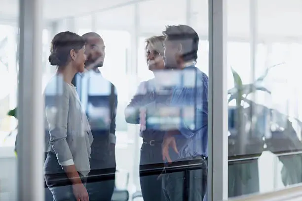 View of businesspeople conversing through glass wall in office