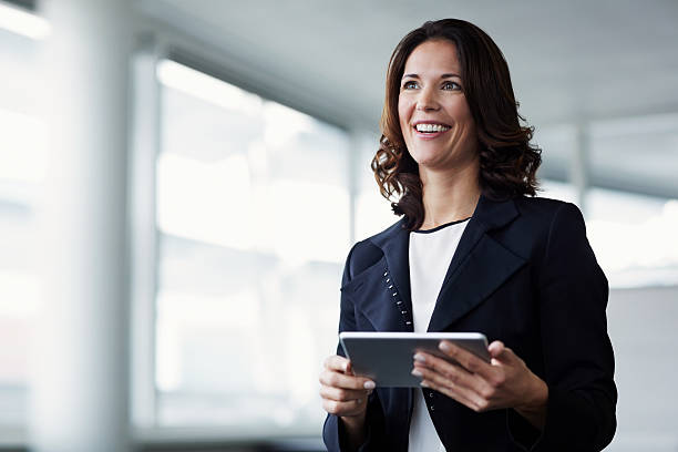 happy businesswoman holding digital tablet - ejecutiva fotografías e imágenes de stock