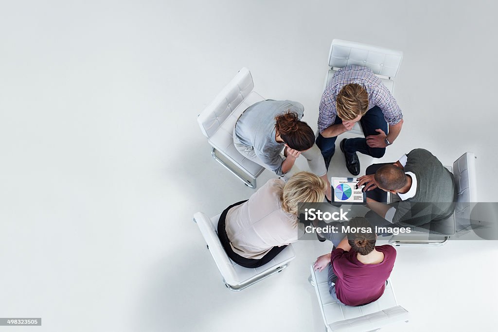 Businesspeople using digital tablet together High angle view of businesspeople using digital tablet together in office Teamwork Stock Photo