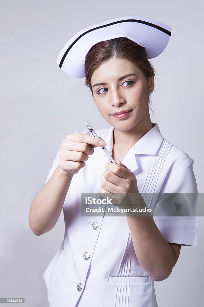 Brunette bellezza giovane infermiera con una siringa di ipodermico fuoco - Foto stock royalty-free di Accessorio personale