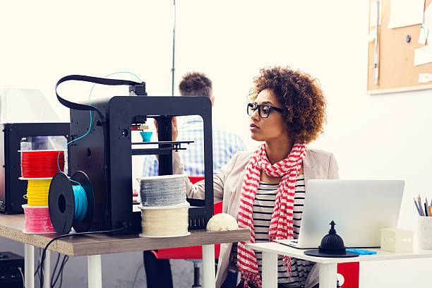 3D printer office Mixed race young woman working in a 3d printer office, watching at 3d printout. 3d printing filament photos stock pictures, royalty-free photos & images