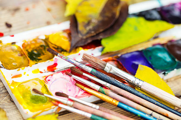istock Plastic paint palette with paint, brushes and yellow leaves 498335186