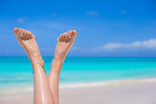 istock Close up of female legs on white sandy beach 498336403