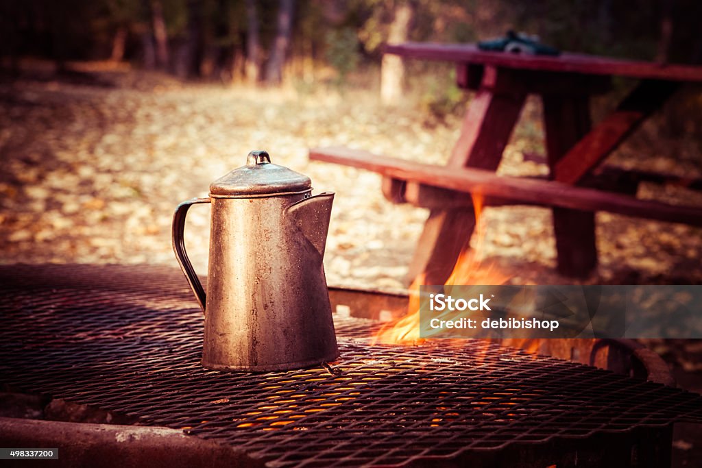 Coffee Brewing On A Campfire Cowboy coffee brew percolating on a campfire grate. Campground picnic table in background. No people in image. High resolution color photograph with copy space. Horizontal composition. 2015 Stock Photo